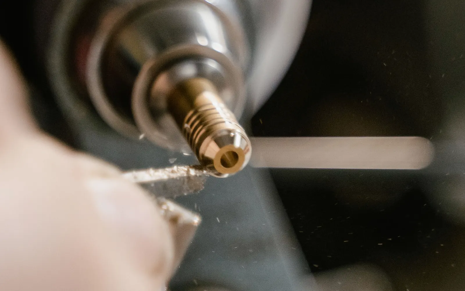 A brass component being turned on a lathe